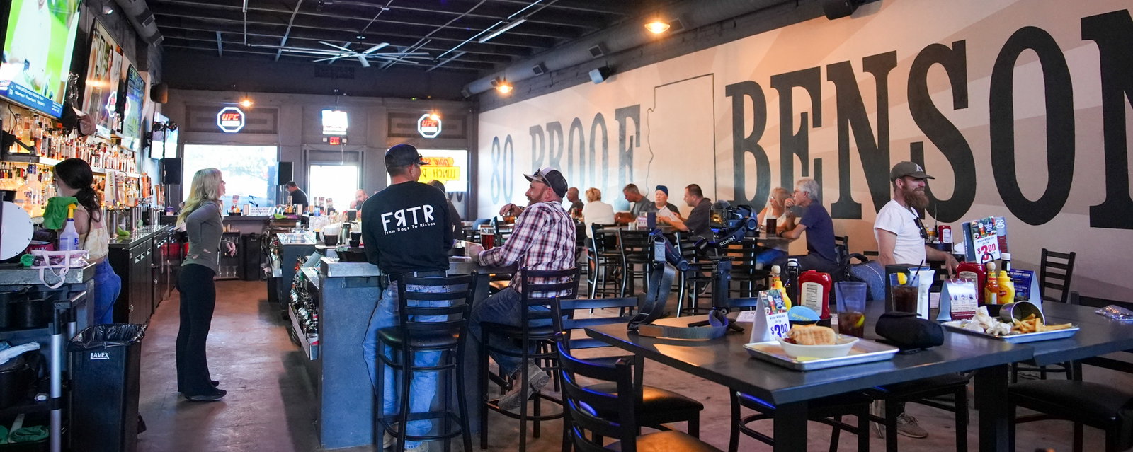 Inside 80 Proof — the bar and the '80 Proof Benson' wall mural, packed with regulars